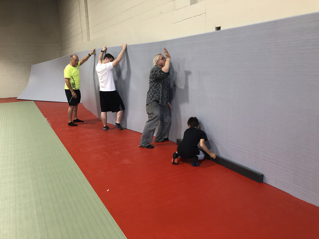 Fitting wall padding beside the completed training surface.